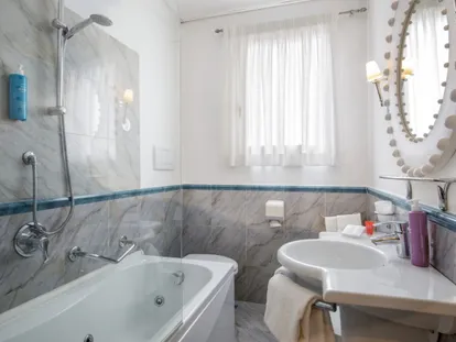 Bathroom with bathtub and grey tiling in the Executive Double room