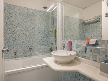 Mosaic-tiled bathroom with bathtub and washbasin in the Executive Double room