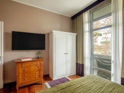 Wardrobe, chest of drawers and TV in the Executive Double room, with a small balcony